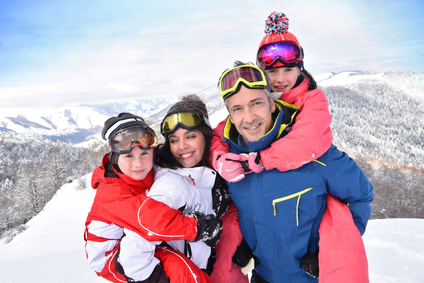 Parents et enfants debout dans la neige aux sports d'hiver