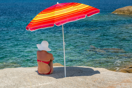 Femme à l'abri d'un parasol regarde la mer