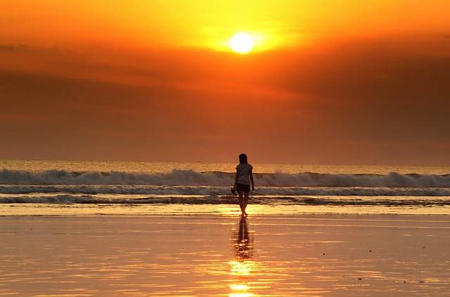 Coucher de soleil sur une plage avec jeune femme à l'horizon