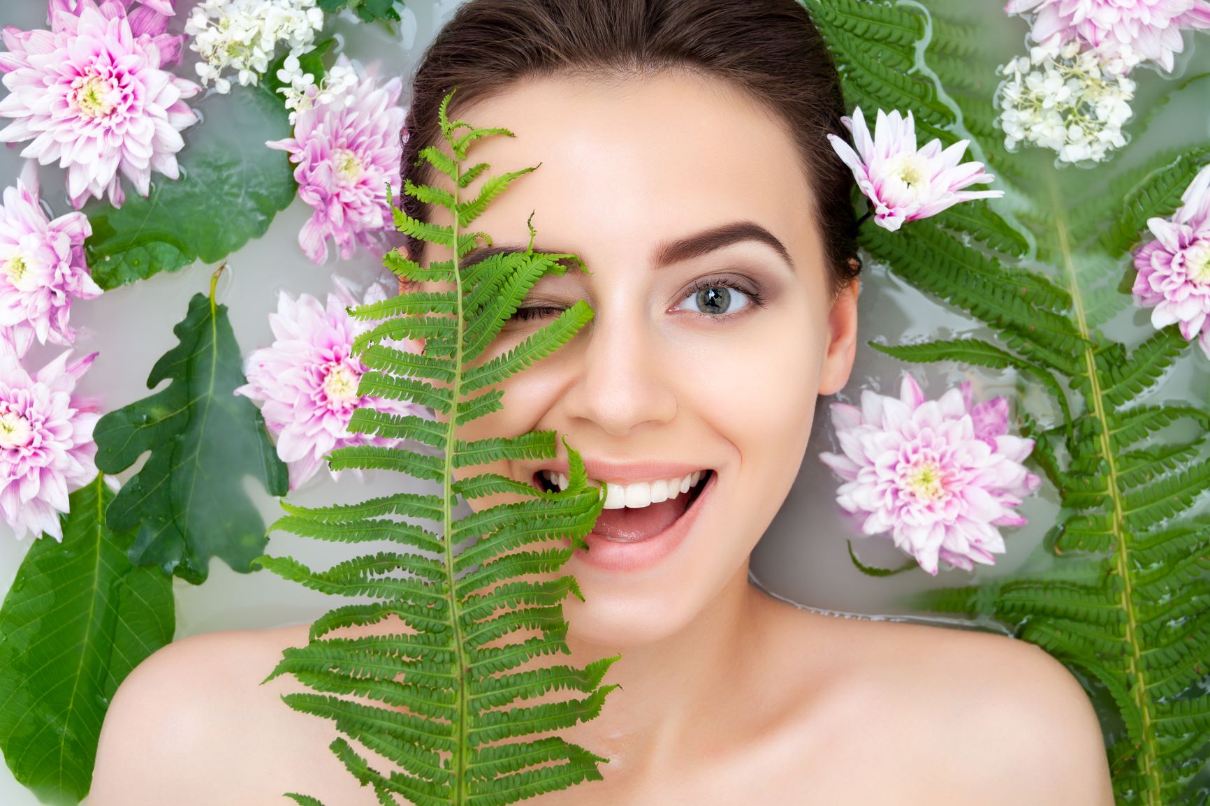 femme dans un bain avec des feuilles et fleurs