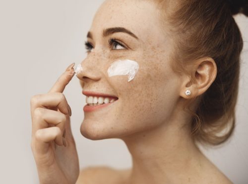 femme appliquant de la crème sur son visage